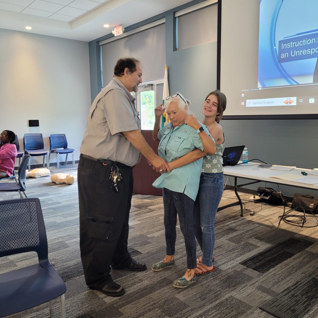 A woman demonstrates the Heimlich Maneuver 