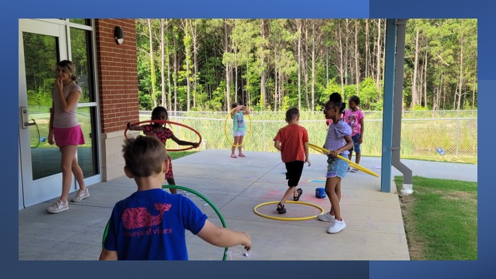 Children hula hoop outside.