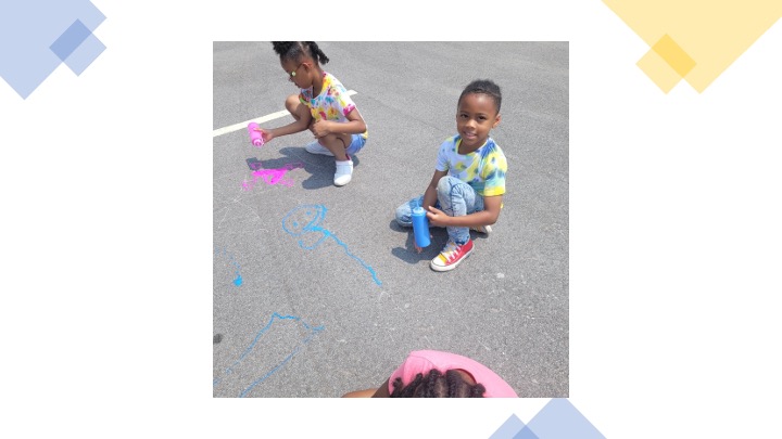 Children painting in a parking lot with chalk.