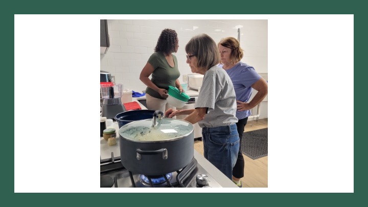 Women watch a pot boiling on a stove