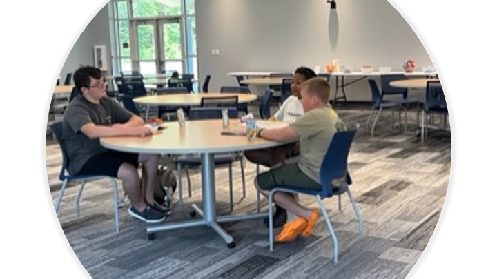 Kids sit around a table having a snack.