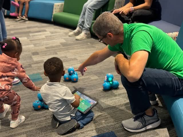 man and children practice coding with interactive 4-H robots