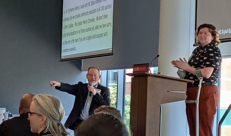 Kenny Sherin speaks onstage about the NC Digital Futures Program while Jess Epsten stands nearby during the NC Digital Opportunity Gathering.
