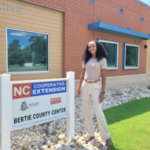 A woman standing by a sign that reads NC Cooperative Extension, Bertie County Center